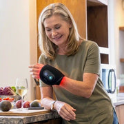 Woman wearing the CiraWrap heated wrist massager during an everyday kitchen routine